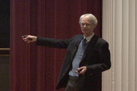 Claiborne Glover gestures as he delivers his lecture on the Origins of Biomolecules on the stage of the UGA Chapel